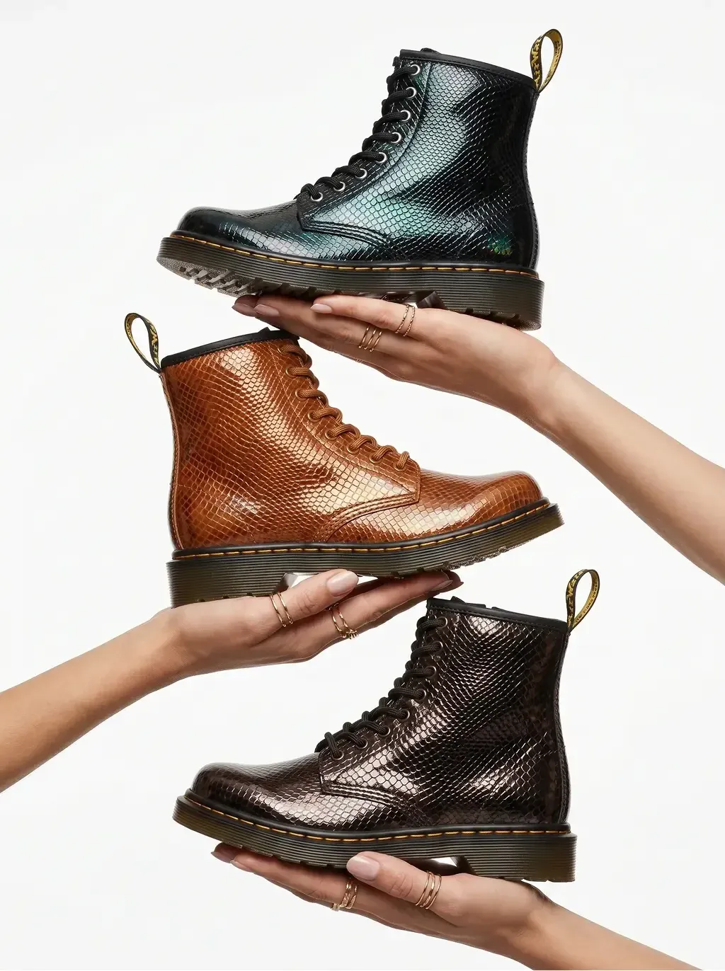 Studio product photography of three 8-eyelet lace-up combat boots held