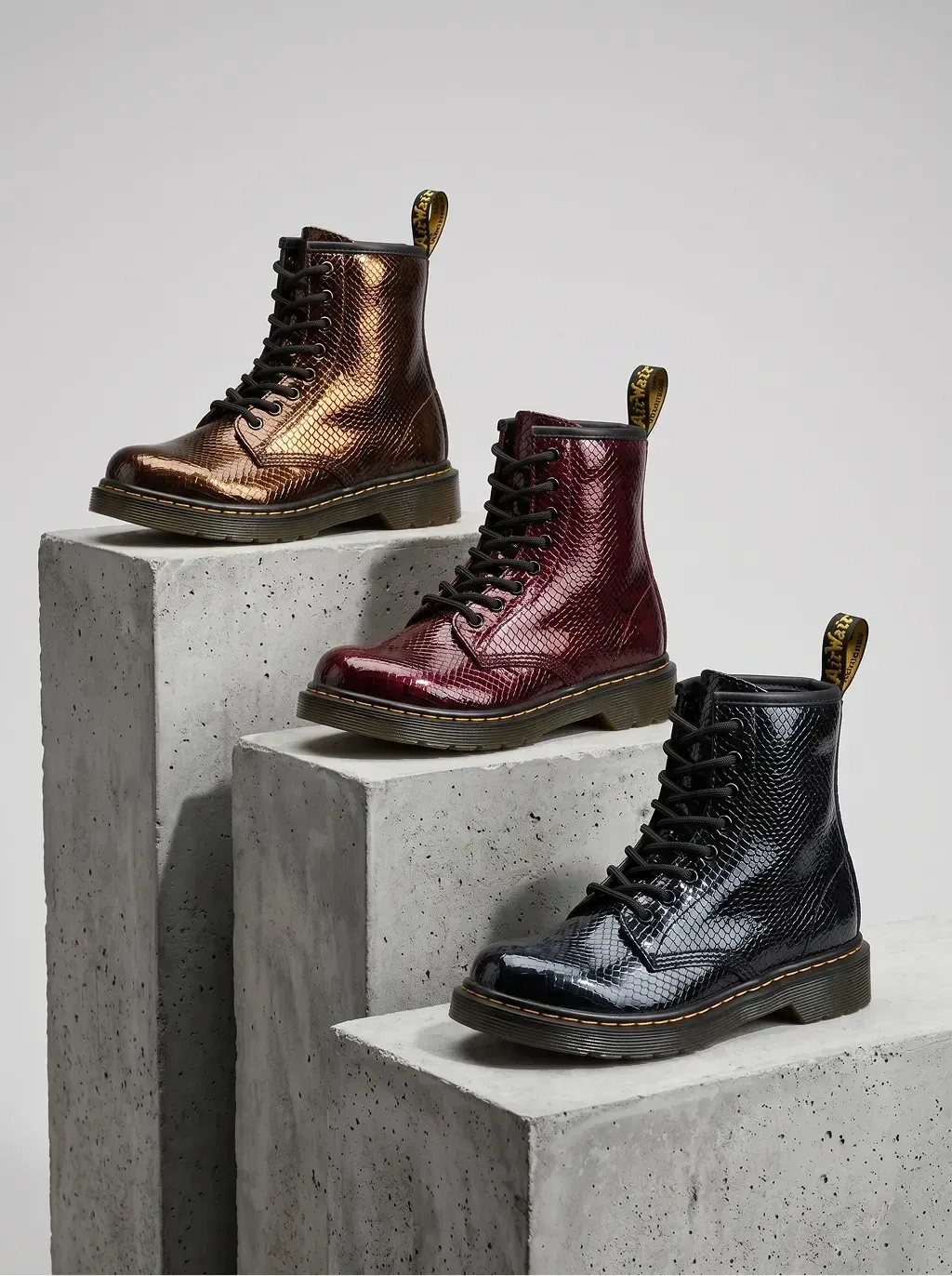 Studio product photography of three 8-eyelet lace-up combat boots with