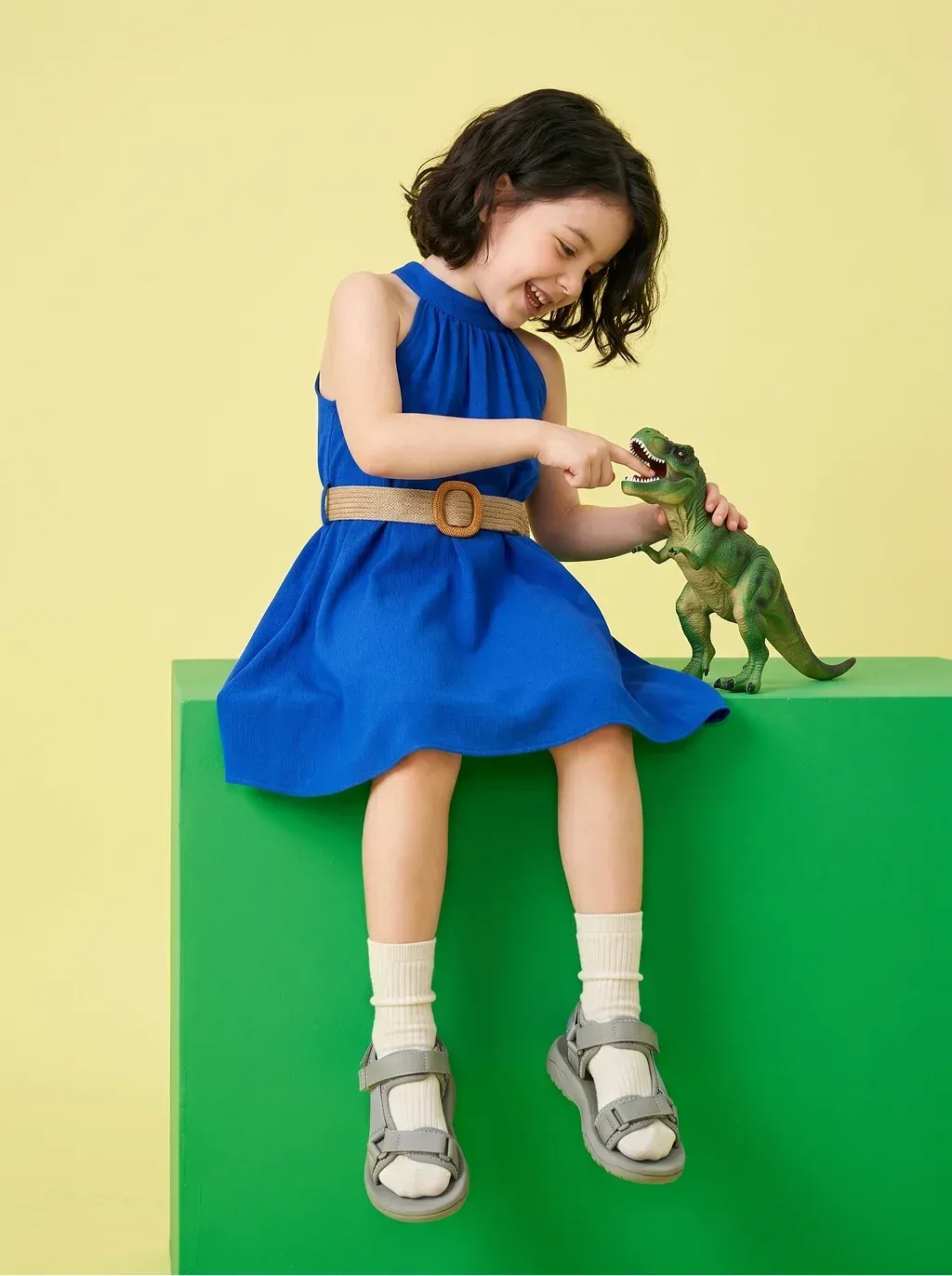 Playful studio editorial photograph of a laughing little girl with
