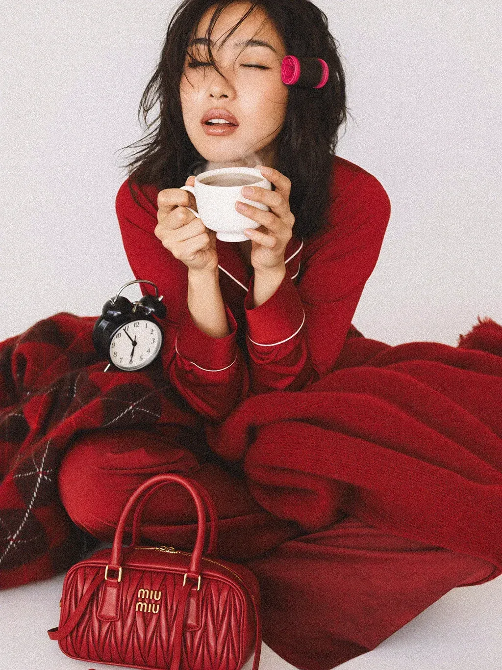 Editorial fashion photograph of a young woman sitting wrapped in