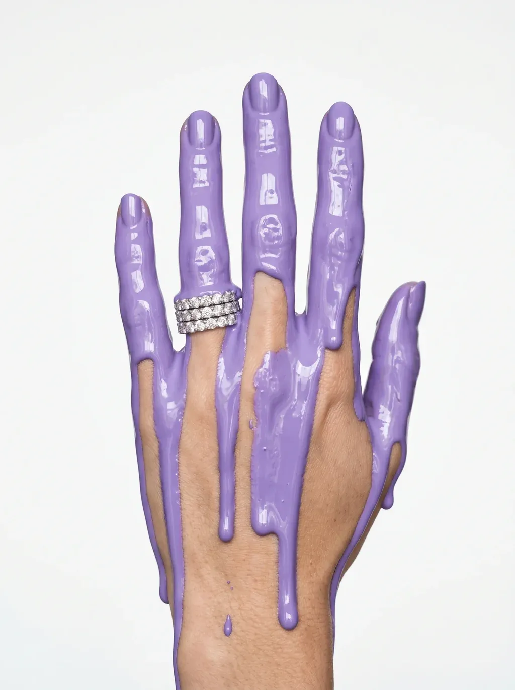 A high-fashion jewelry editorial photograph of a woman's hand raised