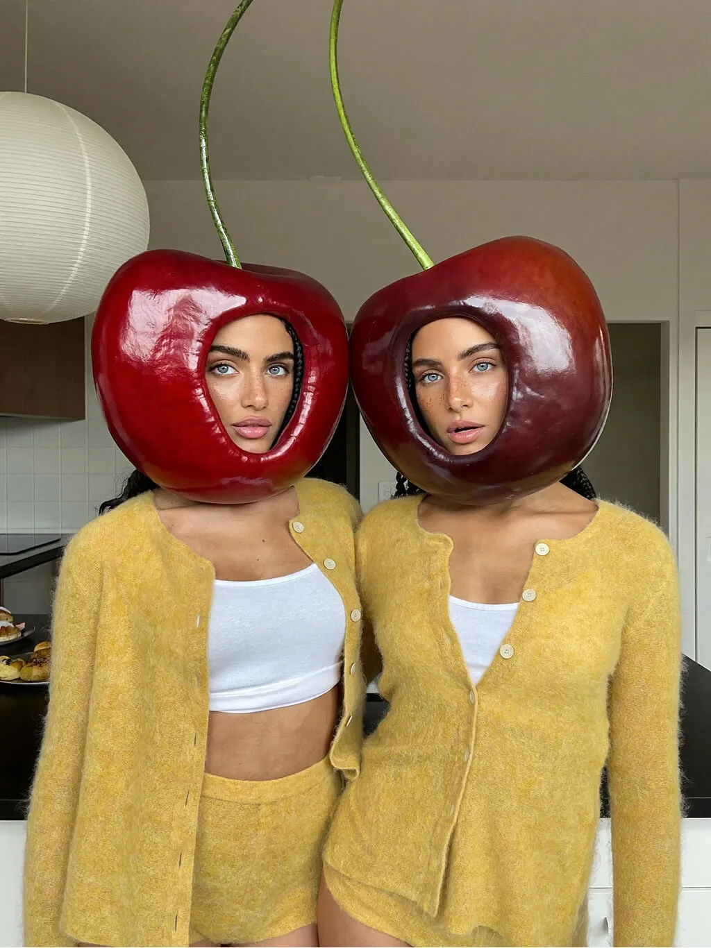 A surreal fashion editorial photograph of two identical twin women