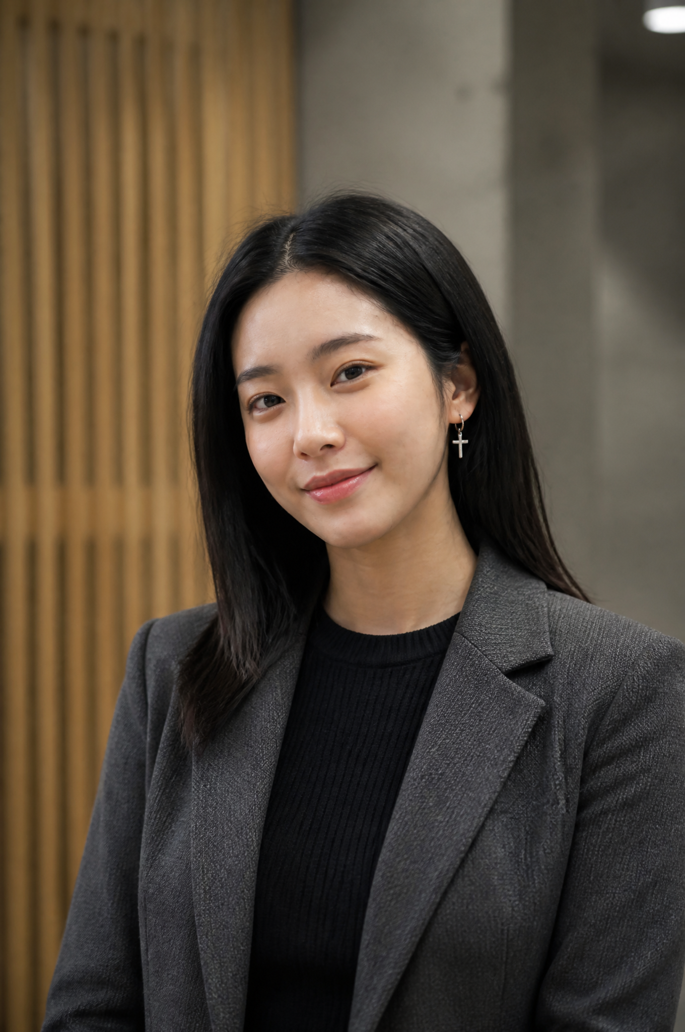A young East Asian woman with shoulder-length dark hair stands in a professional interior…