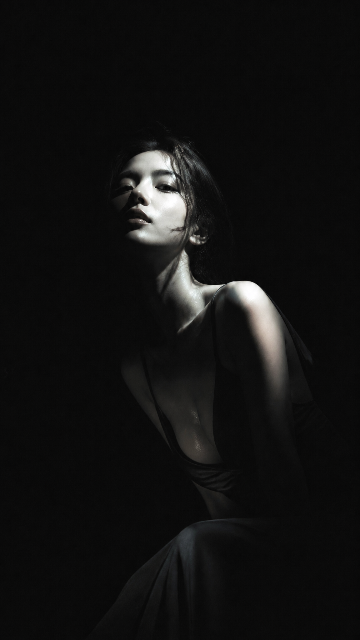 暗黑极简冷光半写实插画，主体为身穿深色低领长裙的漂亮韩国女明星，眼神冷峻，面容俊俏，纯黑背景，大面积黑场吞没画面，侧上方冷白硬光局部照亮主体，强烈明暗切割，高反差低照度，黑白灰低…