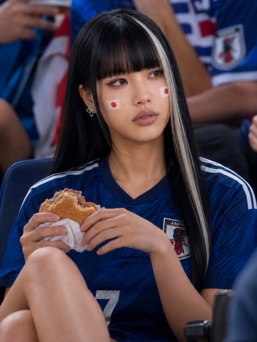 Ultra-realistic portrait of a stylish young woman at a packed football stadium, wearing a…