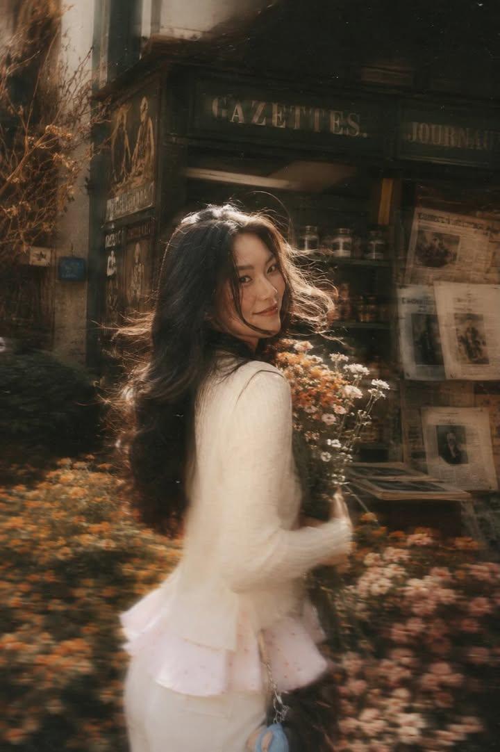 A beautiful young woman with long dark flowing hair holding a bouquet of soft pink roses,…