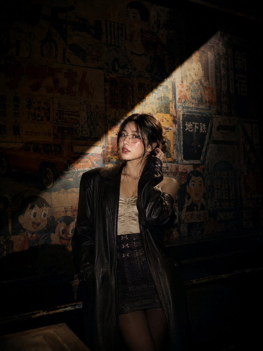 Cinematic nighttime portrait of a stylish young Asian woman standing on an escalator insi…