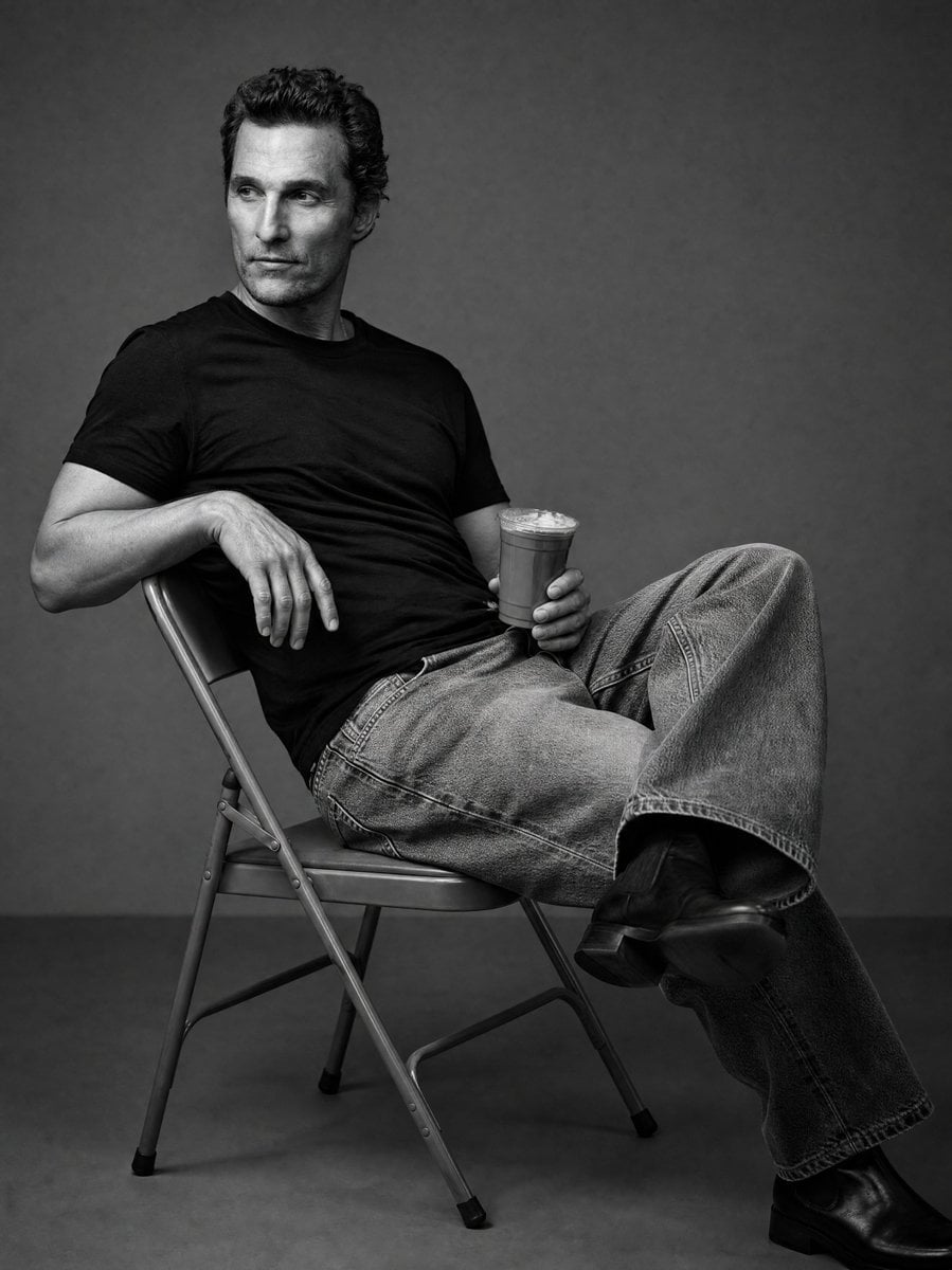 Create a black and white studio image of the person in the uploaded image, sitting casual…