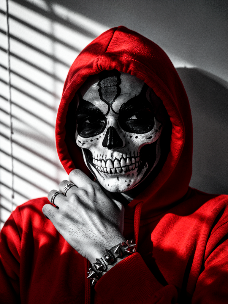 A close-up portrait of a person wearing a vibrant red hooded sweatshirt, with the rest of…