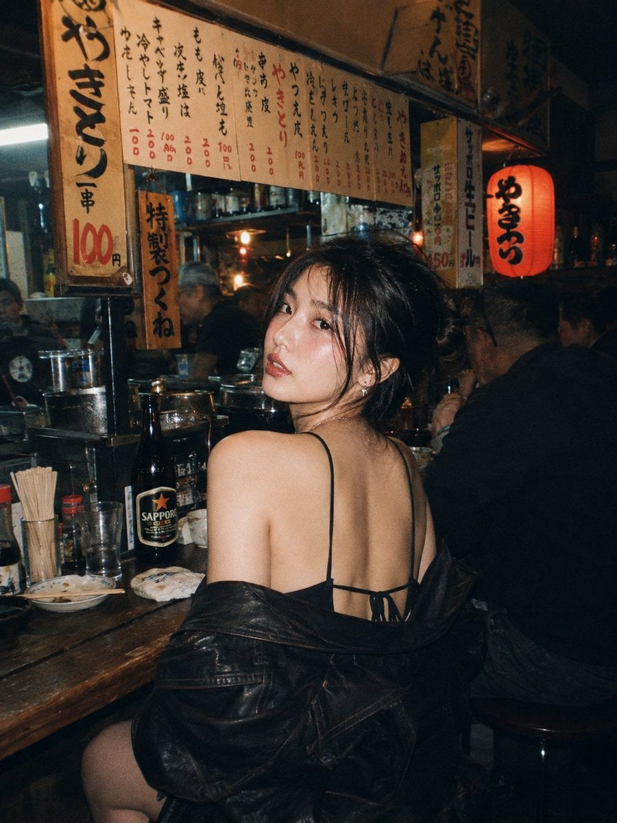A beautiful young East Asian woman with long dark wavy hair and striking makeup, sitting …