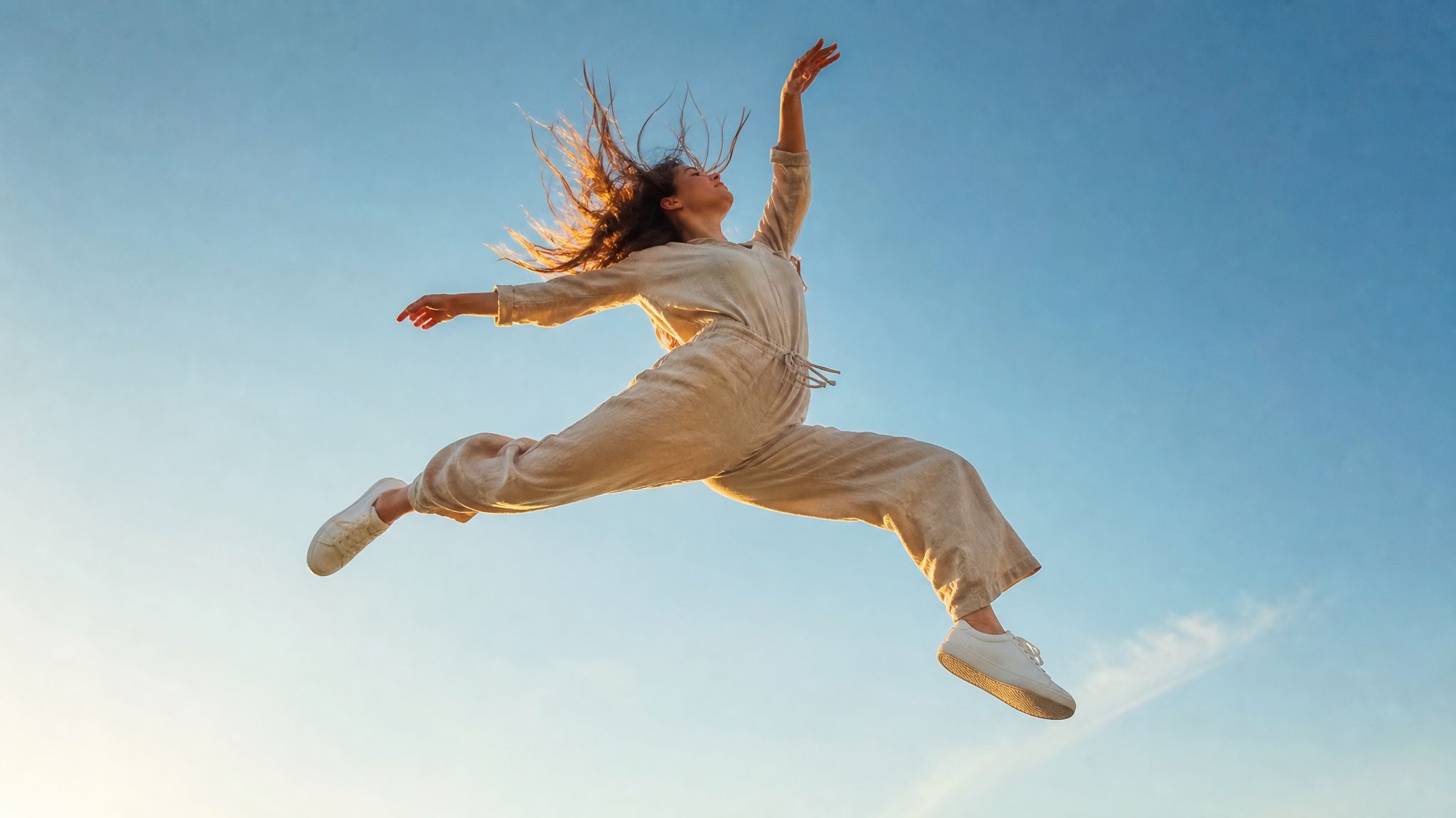 A young woman captured mid-air in a dynamic, gravity-defying leap, her body angled sharpl…