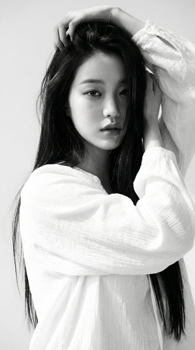 Black-and-white portrait of a young woman with long straight dark hair, wearing a loose w…