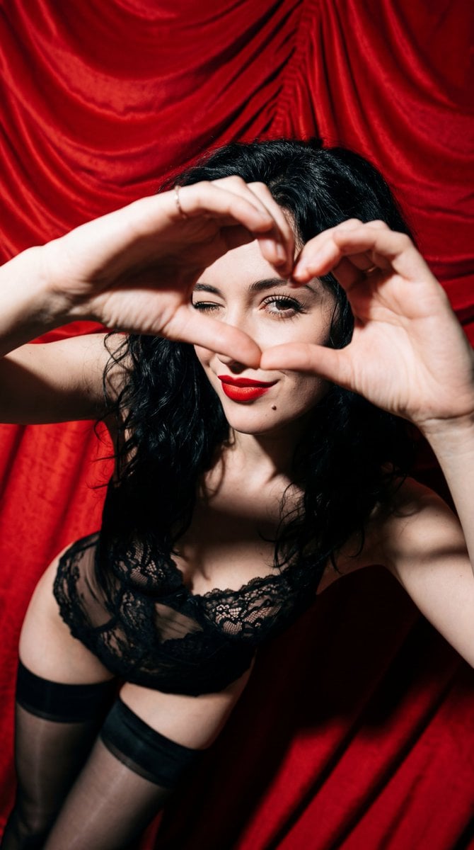 Subject: A young woman with wavy, tousled jet-black hair. She has a flirtatious expressio…