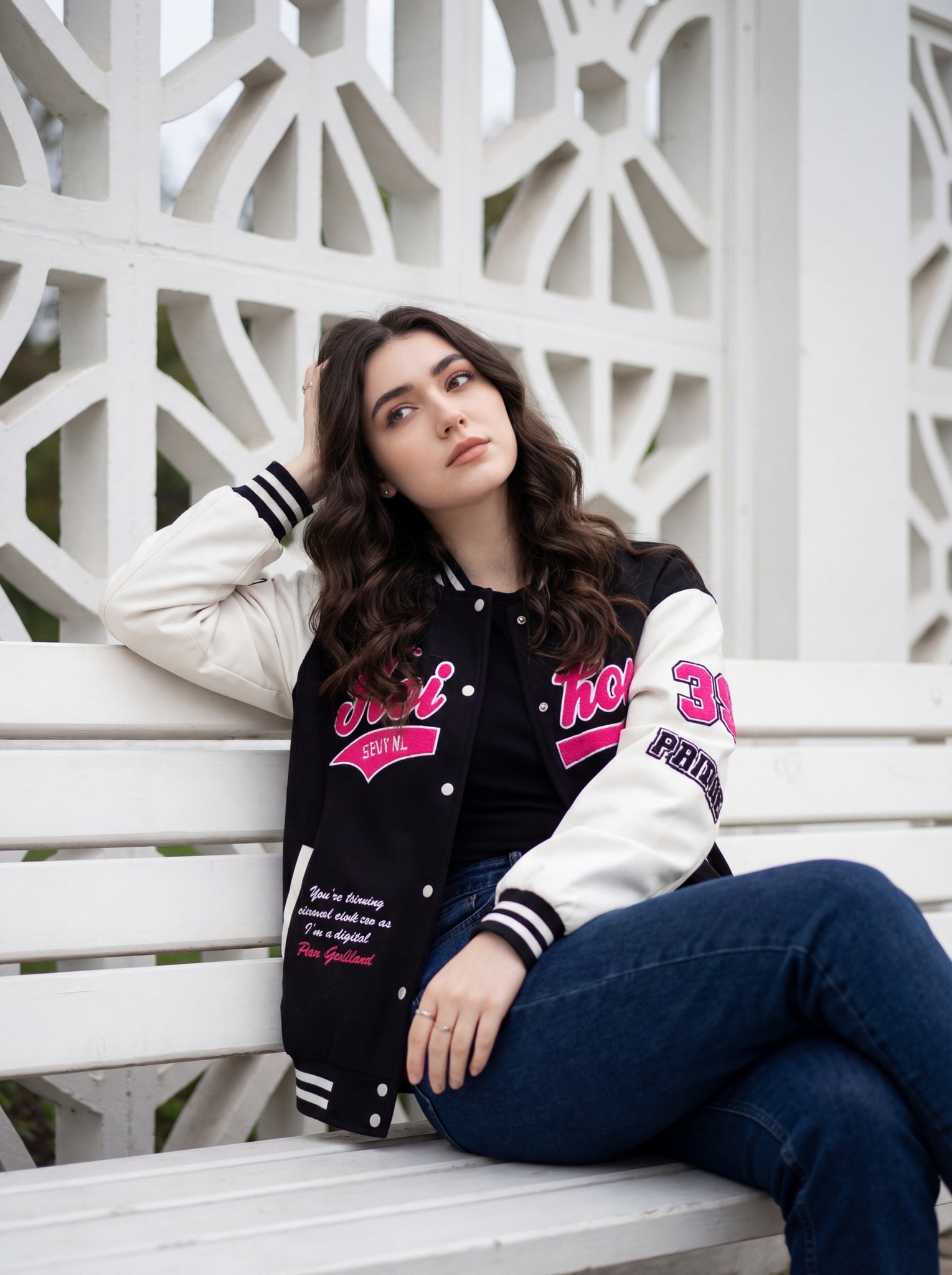 A young woman is sitting casually on a white wooden bench, positioned slightly off-center…